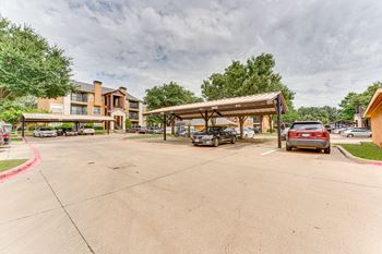 A parking lot with cars and a building in the background at Limestone Ranch Apartments, Lewisville, TX